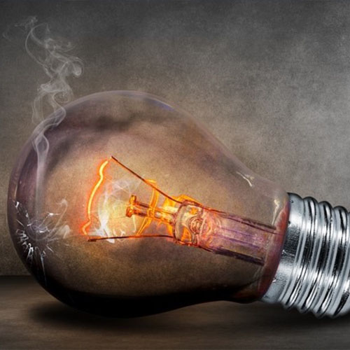 A cracked, smoking lightbulb lying on a table, symbolizing burnout, depression, and anxiety.